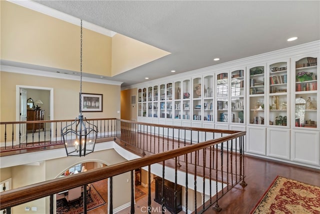 corridor with ornamental molding, a chandelier, a textured ceiling, and dark wood-type flooring