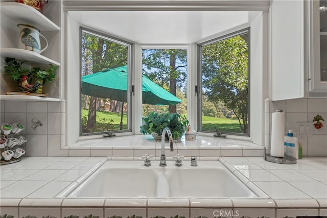 kitchen featuring tile countertops, sink, tasteful backsplash, and white cabinetry