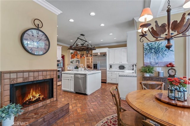 kitchen with a kitchen island, appliances with stainless steel finishes, a fireplace, and white cabinetry