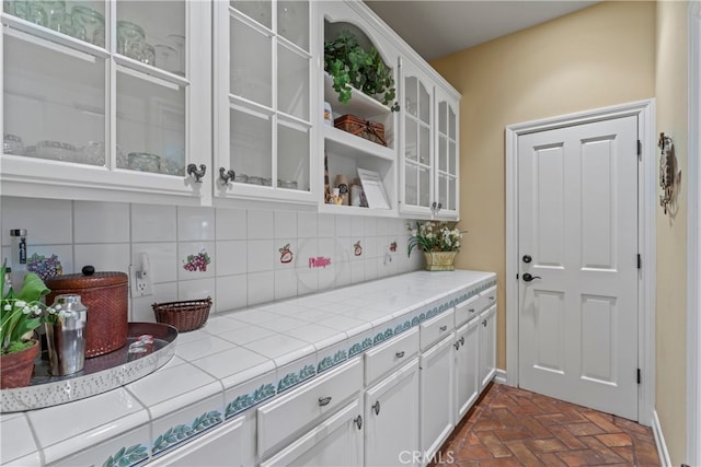 kitchen with tile countertops, white cabinetry, and decorative backsplash