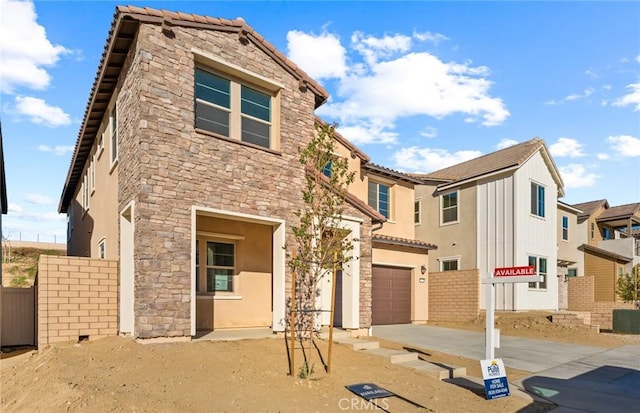 21239 W Wildflower Way, Chatsworth, CA 91311 - view of front of home featuring driveway, an attached garage, stone siding, and stucco siding
