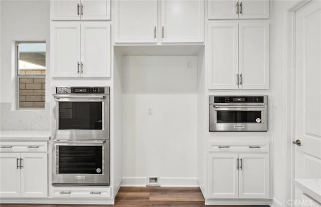 21239 W Wildflower Way, Chatsworth, CA 91311 - kitchen with stainless steel double oven, dark wood-style flooring, and white cabinets
