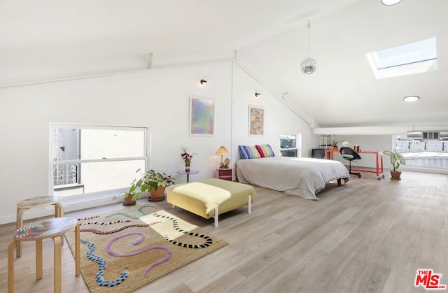 bedroom with a skylight, light hardwood / wood-style floors, and high vaulted ceiling