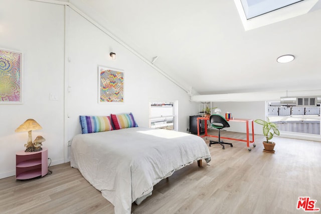 bedroom with high vaulted ceiling, light hardwood / wood-style floors, and a skylight