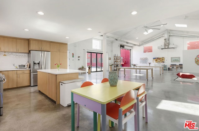 kitchen featuring appliances with stainless steel finishes, vaulted ceiling, tasteful backsplash, a center island, and ceiling fan