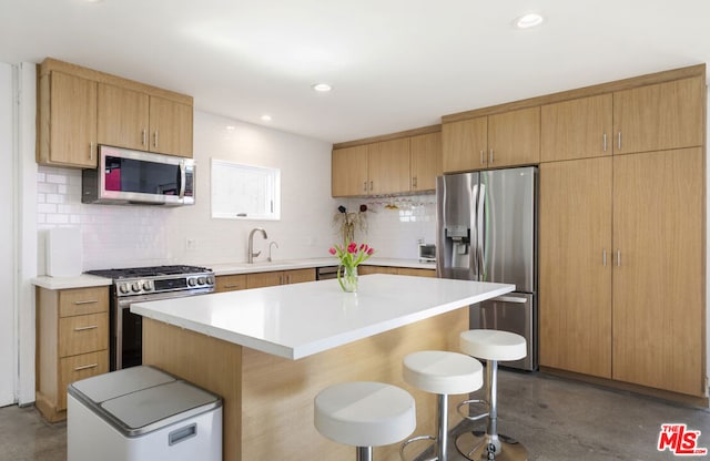 kitchen with tasteful backsplash, a kitchen island, concrete flooring, appliances with stainless steel finishes, and a breakfast bar