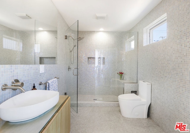 bathroom with vanity, tile walls, toilet, and an enclosed shower