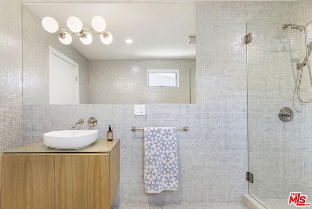 bathroom featuring tile walls, a shower with shower door, and vanity