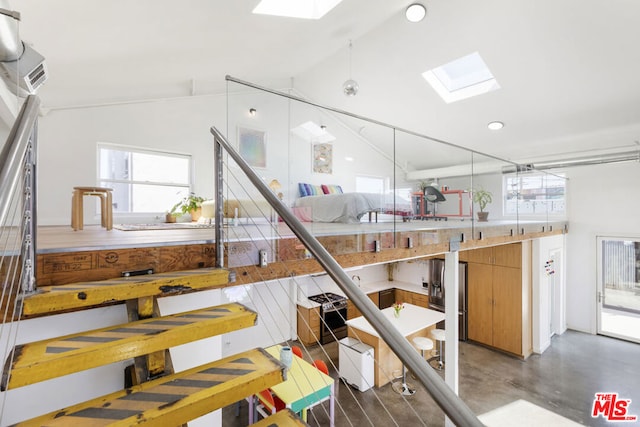 stairway with concrete flooring and vaulted ceiling with skylight