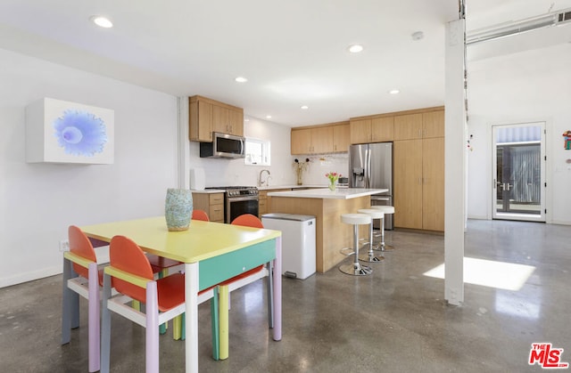 kitchen with sink, a kitchen island, backsplash, stainless steel appliances, and a kitchen breakfast bar