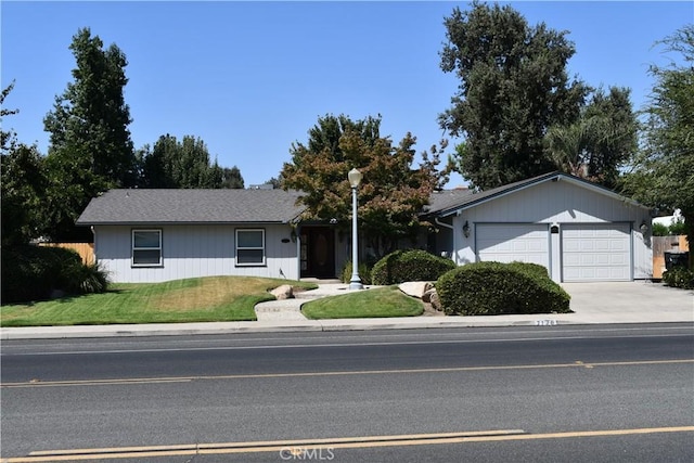 single story home featuring an attached garage, a front lawn, and concrete driveway