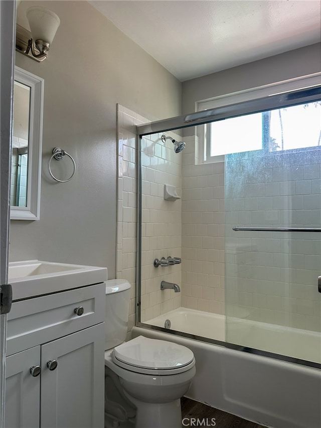 full bathroom with shower / bath combination with glass door, vanity, toilet, and hardwood / wood-style flooring