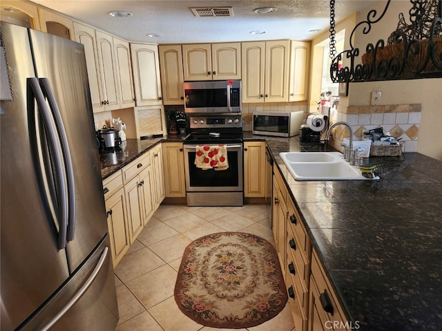 kitchen with a textured ceiling, light tile patterned flooring, sink, and stainless steel appliances