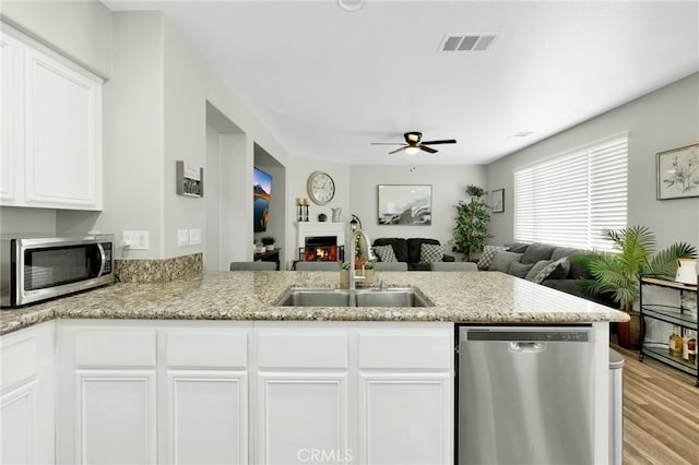 kitchen featuring ceiling fan, kitchen peninsula, white cabinetry, appliances with stainless steel finishes, and light hardwood / wood-style floors