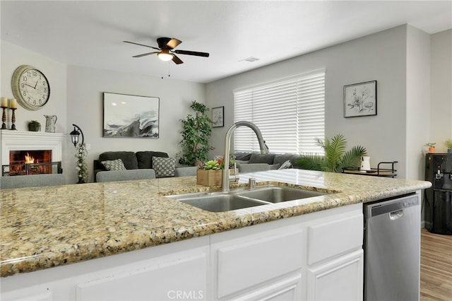 kitchen with light wood-type flooring, sink, white cabinetry, ceiling fan, and stainless steel dishwasher