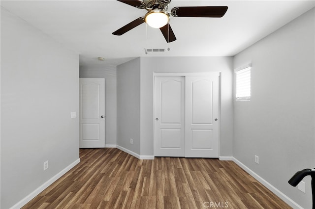 unfurnished bedroom with a closet, ceiling fan, and dark hardwood / wood-style flooring