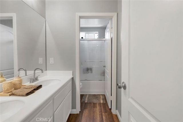 full bathroom with bath / shower combo with glass door, toilet, vanity, and hardwood / wood-style flooring