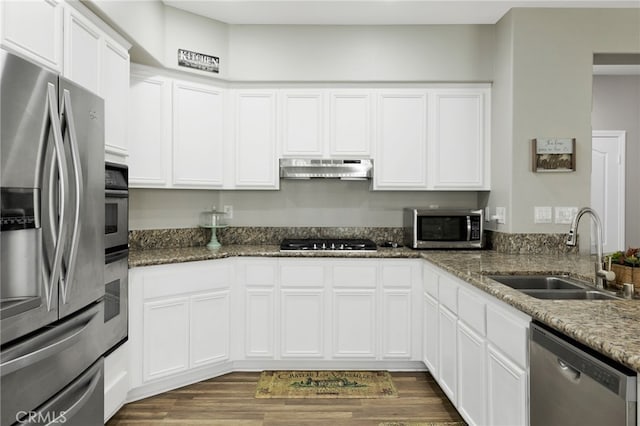 kitchen with dark stone countertops, dark wood-type flooring, white cabinets, stainless steel appliances, and sink