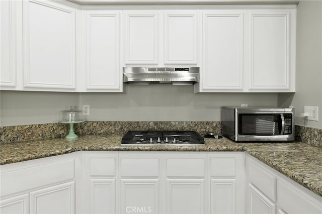 kitchen with appliances with stainless steel finishes, white cabinetry, and extractor fan