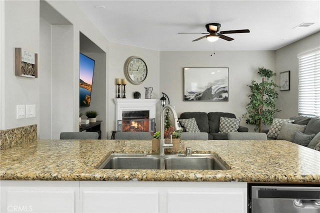 kitchen featuring sink, ceiling fan, light stone counters, and white cabinets