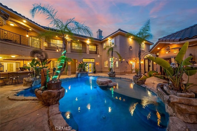 pool at dusk featuring a patio