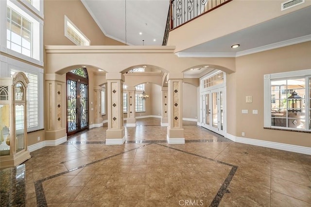 foyer featuring ornate columns, crown molding, french doors, and a high ceiling