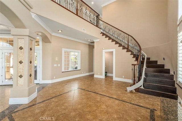 foyer entrance with a towering ceiling and crown molding