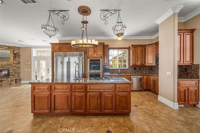 kitchen featuring stainless steel appliances, a notable chandelier, decorative light fixtures, a fireplace, and a center island with sink