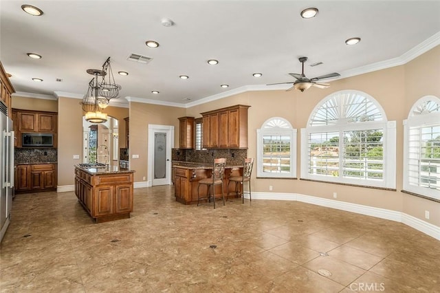 kitchen with pendant lighting, a center island, crown molding, and backsplash