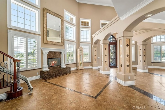 tiled foyer entrance with a towering ceiling, ornate columns, plenty of natural light, and crown molding