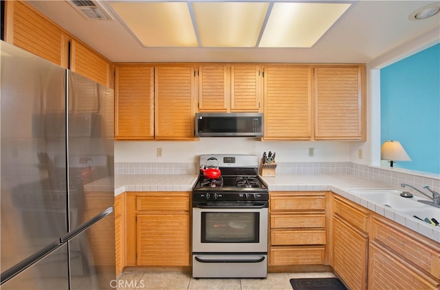 kitchen with tile counters and appliances with stainless steel finishes