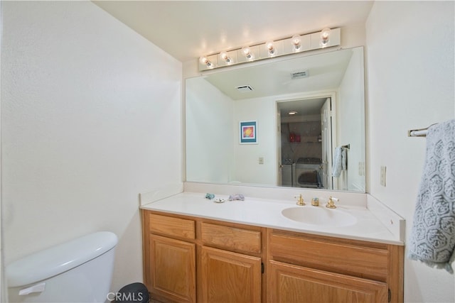 bathroom with vanity, toilet, and washing machine and dryer