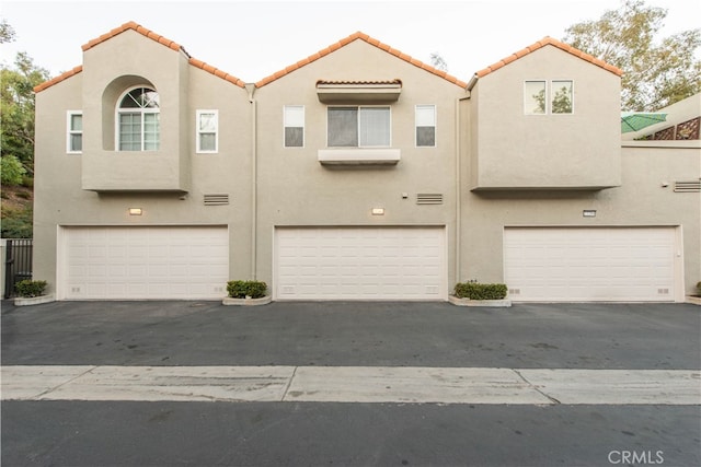 view of front facade with a garage and a wall mounted air conditioner