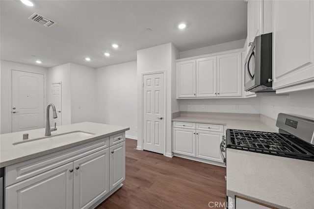 kitchen with sink, dark hardwood / wood-style flooring, a kitchen island with sink, white cabinets, and appliances with stainless steel finishes