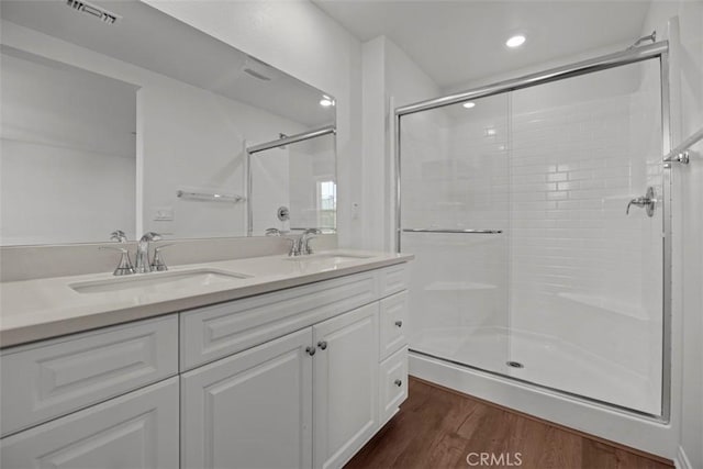 bathroom with vanity, hardwood / wood-style flooring, and a shower with shower door