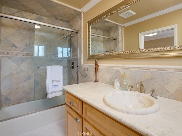 bathroom with vanity, shower / bath combination with glass door, crown molding, and tile walls