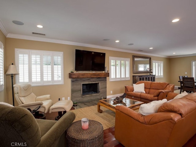 living room featuring hardwood / wood-style flooring, crown molding, and a high end fireplace