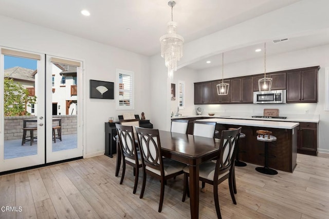 dining space with a chandelier, french doors, and light hardwood / wood-style flooring