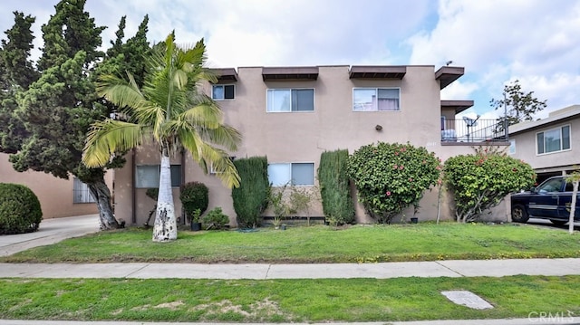 view of front of house with a balcony and a front lawn