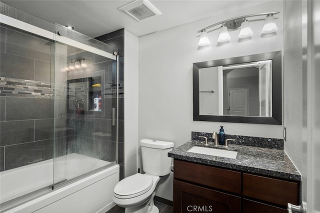 full bathroom with enclosed tub / shower combo, vanity, and toilet