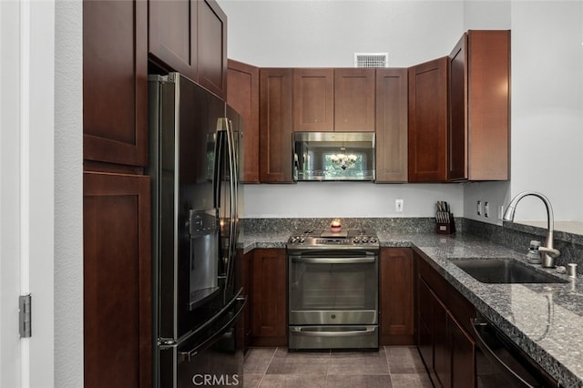 kitchen with dark stone countertops, sink, dark tile patterned floors, and black appliances