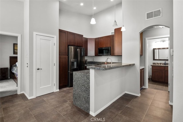 kitchen with decorative light fixtures, stainless steel appliances, a high ceiling, and kitchen peninsula