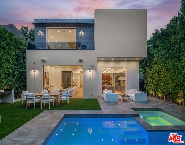 back house at dusk with an outdoor living space, a balcony, a patio area, and a pool with hot tub