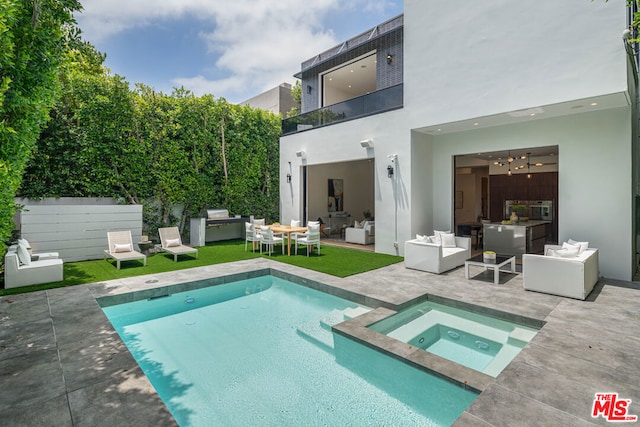 rear view of property featuring an outdoor living space, a swimming pool with hot tub, a balcony, and a patio area