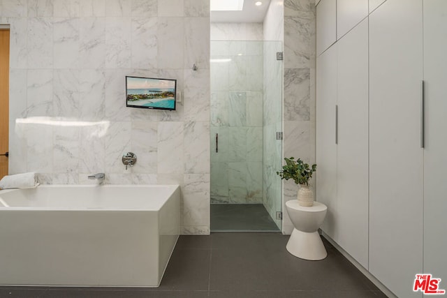 bathroom featuring tile patterned floors, shower with separate bathtub, toilet, and tile walls