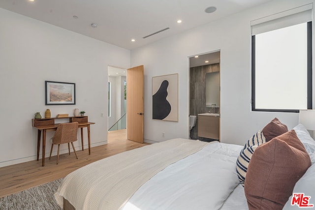 bedroom featuring connected bathroom, light hardwood / wood-style flooring, and multiple windows