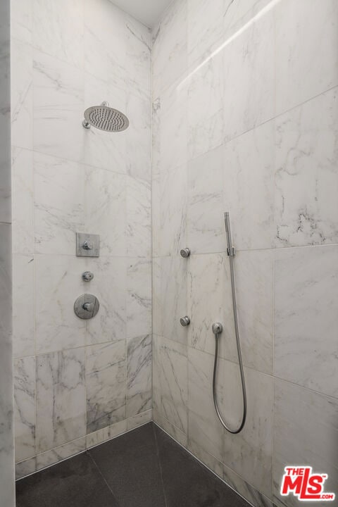 bathroom featuring tiled shower and tile patterned flooring