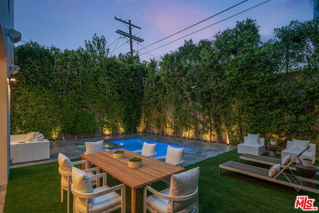 patio terrace at dusk featuring a yard and an outdoor hangout area