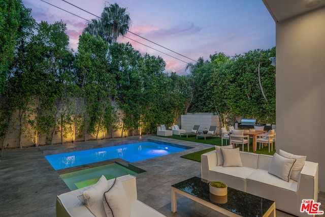 pool at dusk with an in ground hot tub, a patio, and an outdoor hangout area