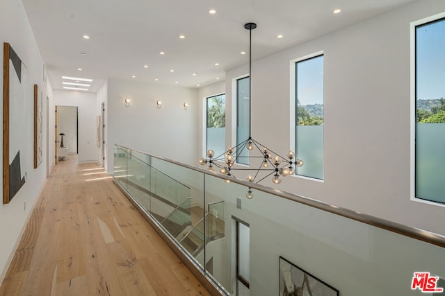 corridor featuring an inviting chandelier and light hardwood / wood-style flooring